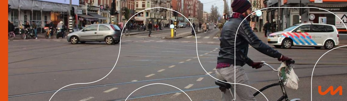 Een drukke straat in Amsterdam met voertuigen en fietsers, die de verkeersveiligheid benadrukt.